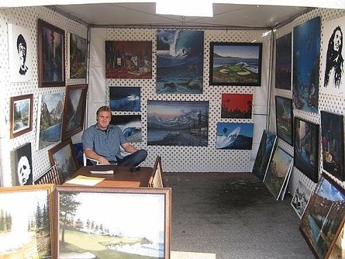 A picture of Wes Van Dyke with his paintings.